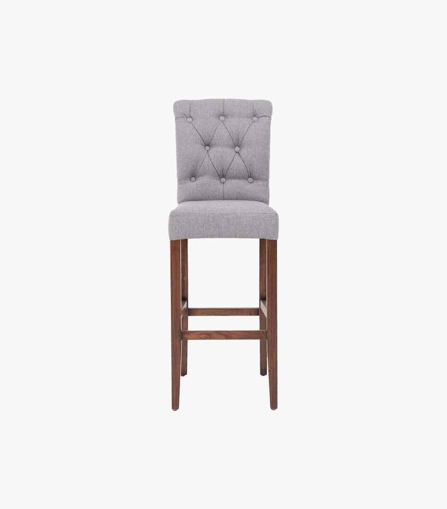 Banco Chester para barra de cocina en madera con asiento de tela gris, estilo moderno y cómodo de la marca Avanti Muebles.
